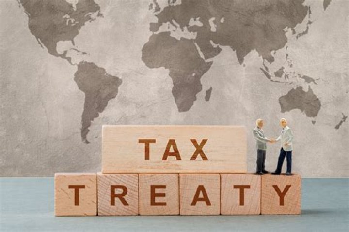 How does a tax treaty eliminate double taxation?